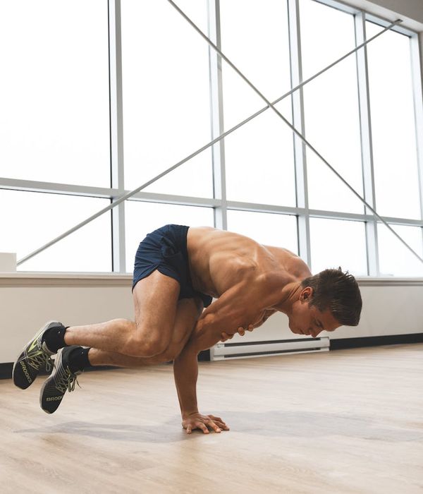 Man in athletic wear performing a controlled strength exercise in a modern studio.